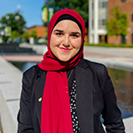 Safiya Khan wearing a black blazer in front of the Johnson Center on Mason's Fairfax Campus