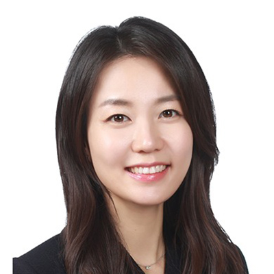 A woman with a black shirt and long black hair stands and smiles