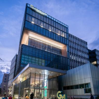 A campus building at dusk with its lights on