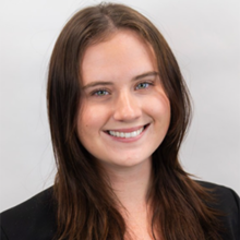 A young woman with long, dark hair wearing a black shirt smiles at the camera.