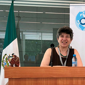 Louise Shelley, founding director of TraCCC, sitting at a table, behind a microphone.