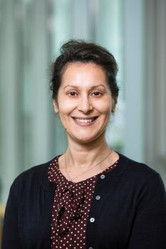 Smiling woman wearing a polka dot blouse and black sweater.