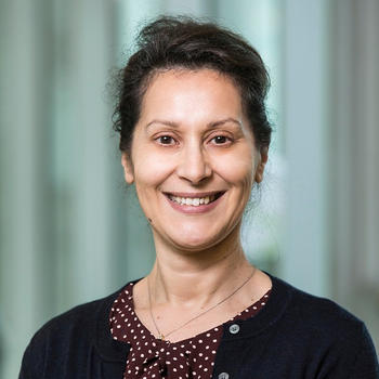 A woman in a black sweater and dotted blouse smiles at the camera.