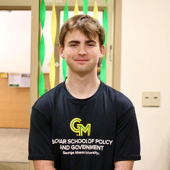 A man in a black tee shirt with a GM on the front gazes at the camera.